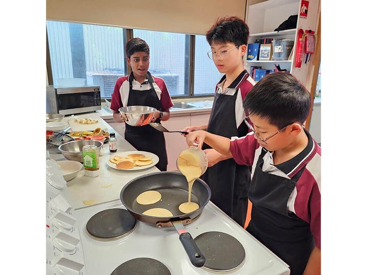A group of students making pancakes in a food technology classroom