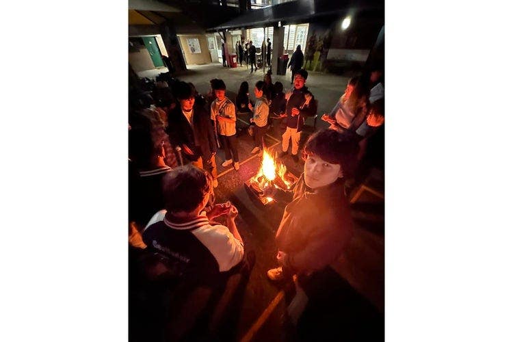 Parents and volunteers engaging with school community at campfire evening an outdoor gathering.